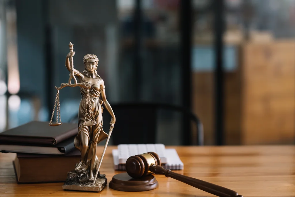 a photo of a uk immigration lawyer desk with the statue of lady justice, a judge gavel and a stack of law books at the ilford, greater london office.