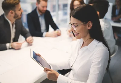 a photo of a law firm business meeting while a lawyer gets good news on her ipad.